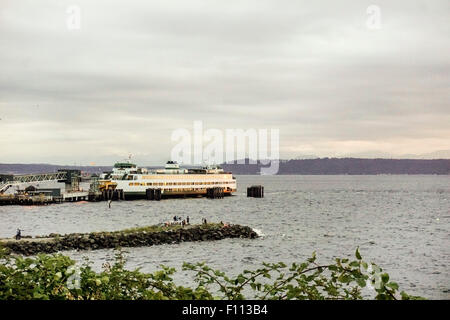 Ansicht von Edmonds Puget sound Waterfront als Menschen auf Stein Steg beobachten Sonnenuntergang mit Fähre im Dock, Olympic Peninsula in Ferne Stockfoto