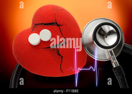 Herz, Stethoskop und Pillen auf rotem Grund Stockfoto