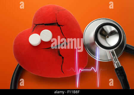 Herz, Stethoskop und Pillen auf rotem Grund Stockfoto
