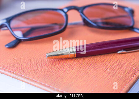 Stift und Gläser auf alte Bücher gelegt. Stockfoto