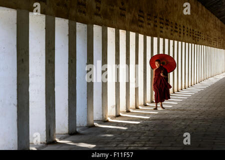 Asiatischer Mönch in der Ausbildung mit Sonnenschirm im Flur Stockfoto