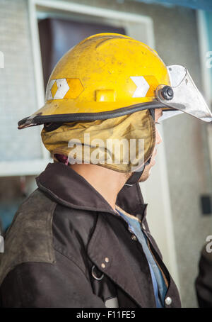 Feuerwehrmann mit gelben Helm im Feuerwehrhaus Stockfoto