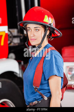 Zuversichtlich Firewoman In roten Helm gegen LKW Stockfoto