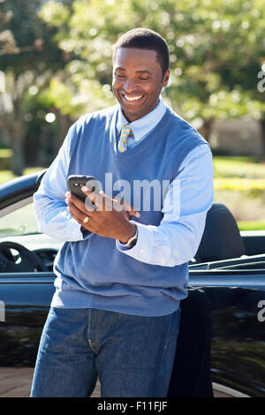 Schwarzer Mann mit Handy am Cabrio Stockfoto