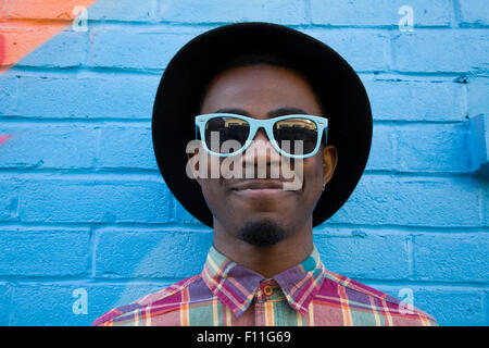 Schwarzer Mann mit Sonnenbrille in der Nähe von bunte Wand Stockfoto