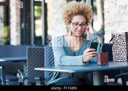 Schwarze Frau mit Handy im café Stockfoto