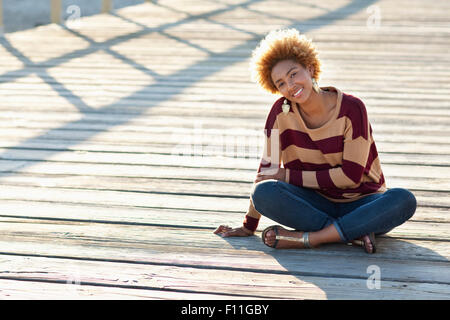 Schwarze Frau sitzen auf Holzsteg Stockfoto