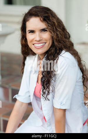 Lächelnde Hispanic Frau sitzen im freien Stockfoto
