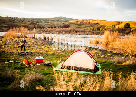 Kaukasischen Mann camping in der Nähe von abgelegenen Fluss, Painted Hills, Oregon, Vereinigte Staaten von Amerika Stockfoto