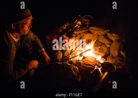 Kaukasischen Mann Essen über Lagerfeuer rösten Stockfoto