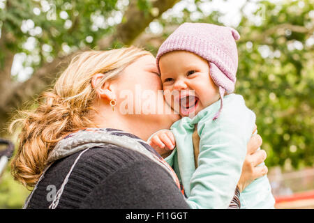 Kaukasische Mutter küssen Baby Tochter im freien Stockfoto