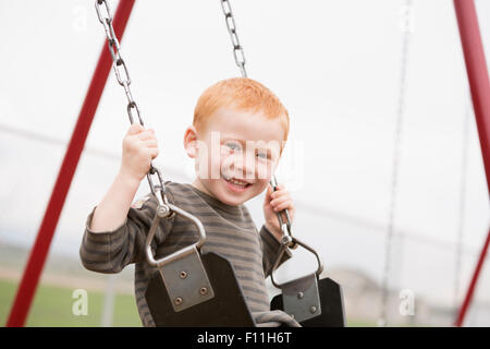 Kaukasische Junge sitzt auf der Schaukel Stockfoto