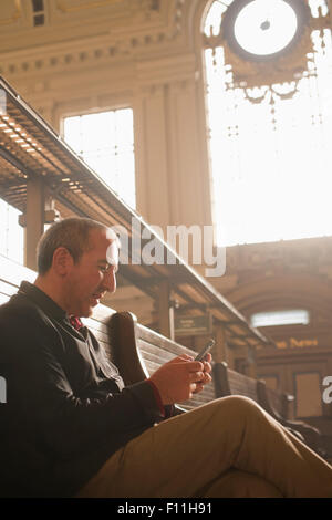 Hispanic Mann liest Zeitung im Bahnhof Stockfoto