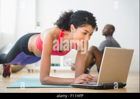 Frau mit Computer und Push-ups im Fitness-Studio Stockfoto