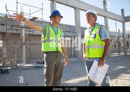 Kaukasische Bauarbeiter sprechen auf Baustelle Stockfoto