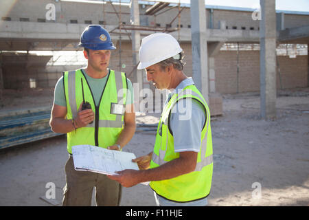 Kaukasische Bauarbeiter sprechen auf Baustelle Stockfoto