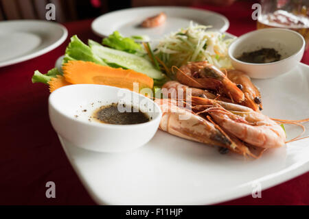 Teller mit Garnelen, Karotten und Salat am Tisch im restaurant Stockfoto