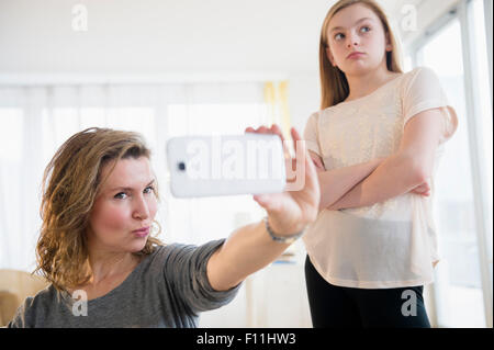 Kaukasische Mädchen peinlich Mutter unter Selfies mit Handy Stockfoto