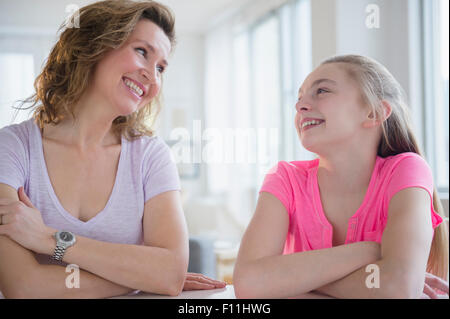 Kaukasische Mutter und Tochter lachend am Tisch Stockfoto