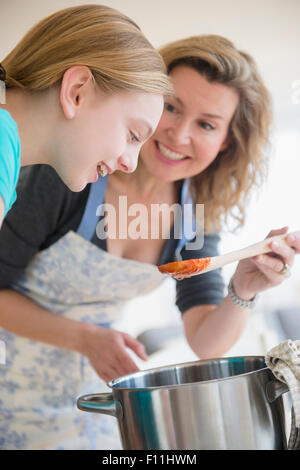 Kaukasische Mutter und Tochter, die Soße im Topf kochen Stockfoto