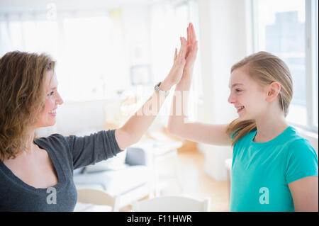 Kaukasische Mutter und Tochter hohe Fiving im Wohnzimmer Stockfoto