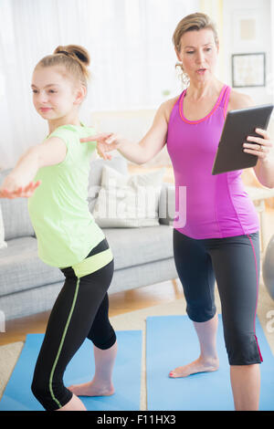 Kaukasische Mutter und Tochter praktizieren Yoga mit digital-Tablette Stockfoto