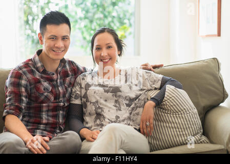 Paar lächelnd auf dem Sofa im Wohnzimmer Stockfoto