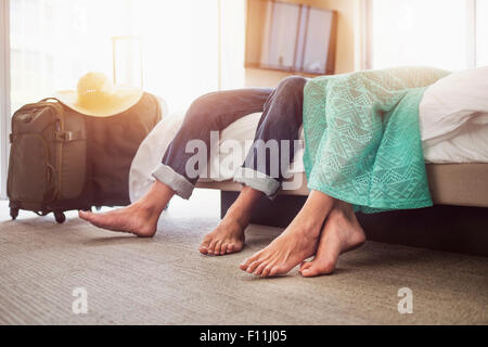 Beine eines Paares auf Bett im Hotelzimmer Stockfoto