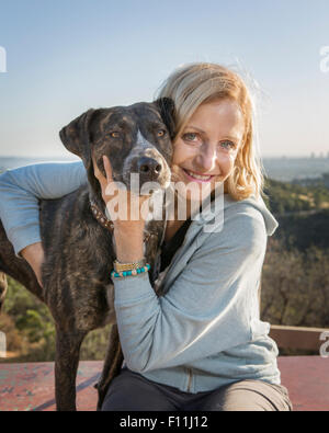 Kaukasische Frau umarmt Hund auf Hügel Stockfoto