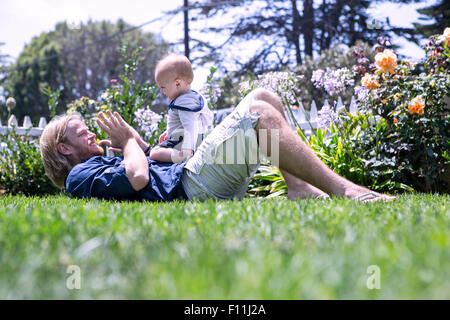 Kaukasische Vater und Sohn spielen in Rasen Stockfoto