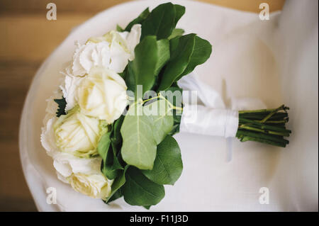 Nahaufnahme von Blumenstrauß auf Hochzeitskleid Stockfoto