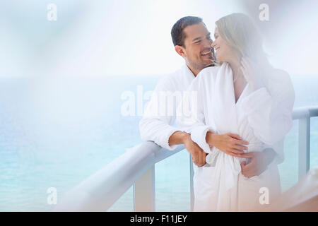 Paar auf Balkon über Meer umarmt Stockfoto