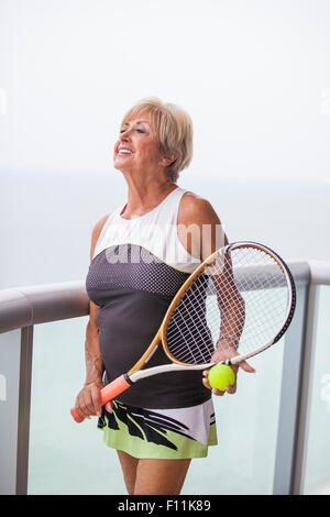 Ältere Frau kaukasischen holding Tennisschläger auf Balkon Stockfoto