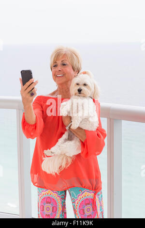 Ältere Frau kaukasischen nehmen Selfie mit Hund auf Balkon Stockfoto