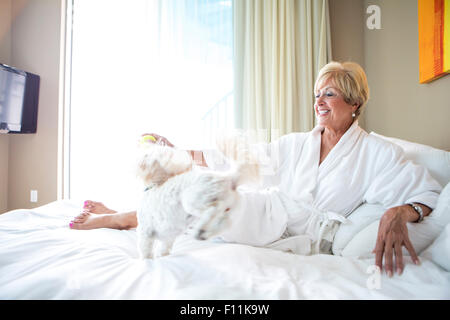 Älteren kaukasischen Frau Petting Hund auf Bett Stockfoto