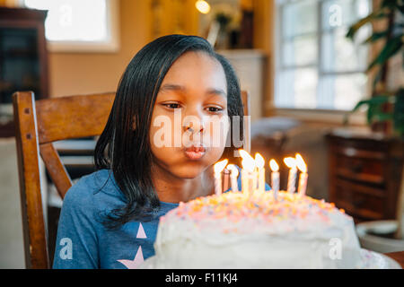 Schwarzes Mädchen bläst Kerzen auf Geburtstagskuchen Stockfoto