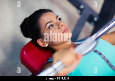 Junge Frau Training mit Langhantel auf der Bank im Fitness-Studio Stockfoto