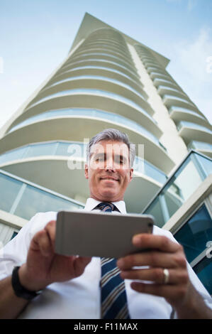 Niedrigen Winkel Ansicht des kaukasischen Geschäftsmann mit Handy am Hochhaus Stockfoto