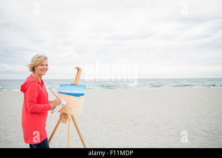 Ältere Frau kaukasischen Malerei am Strand Stockfoto