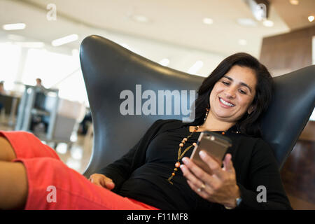 Hispanische Geschäftsfrau mit Handy im Flughafen Stockfoto