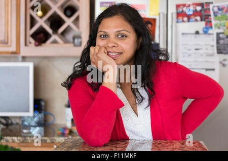 Indische Frau stützte sich auf Küchentheke Stockfoto