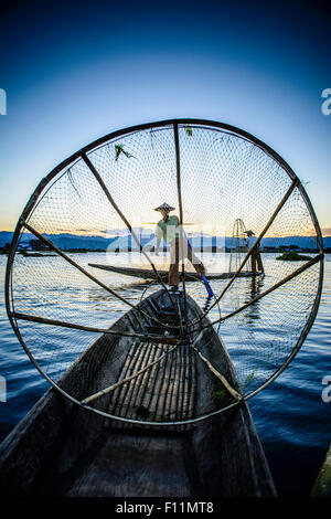 Asiatische Fischer mit Fischernetz im Kanu auf dem Fluss Stockfoto