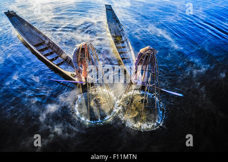 Erhöhte Ansicht der asiatischen Fischer mit Fischernetz in Kanus am Fluss Stockfoto