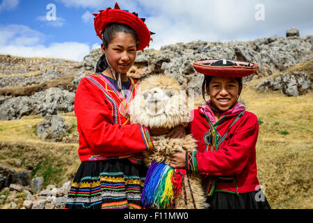Hispanische Schwestern lächelnd mit Lamas in ländlichen Landschaft Stockfoto