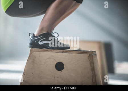 Athlet kauert auf Plattform im Fitness-Studio Stockfoto