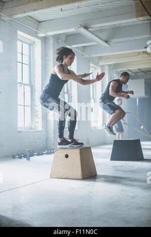 Athleten springen auf Plattformen im Fitness-Studio Stockfoto