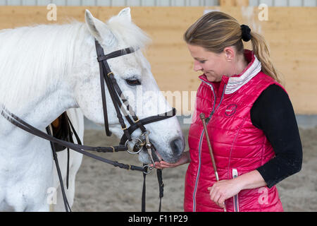 Deutsch Reiten Pony Reiter nach dem Reiten Lektion geben weiße Pony behandeln Stockfoto