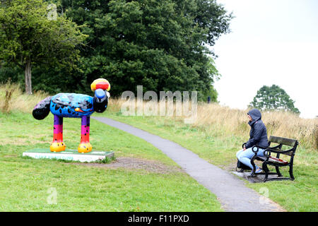 Durch den Regen ein Besucher sitzt an einem Shaun das Schaf Charakter Aussehen abschrecken. Teil des Bristol Shaun in der Stadt Schafe Trail 2015. Stockfoto