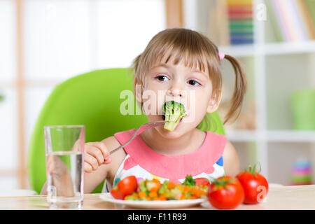 Niedliche kleine Mädchen isst Gemüsesalat mit Gabel Stockfoto