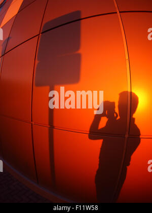 Der Schatten eines Mannes an eine Wand rot-Orange, eine Straße Fotos melden Sie sich am Abend bei Sonnenuntergang mit Weitwinkel fisheye-Objektiv und Stockfoto